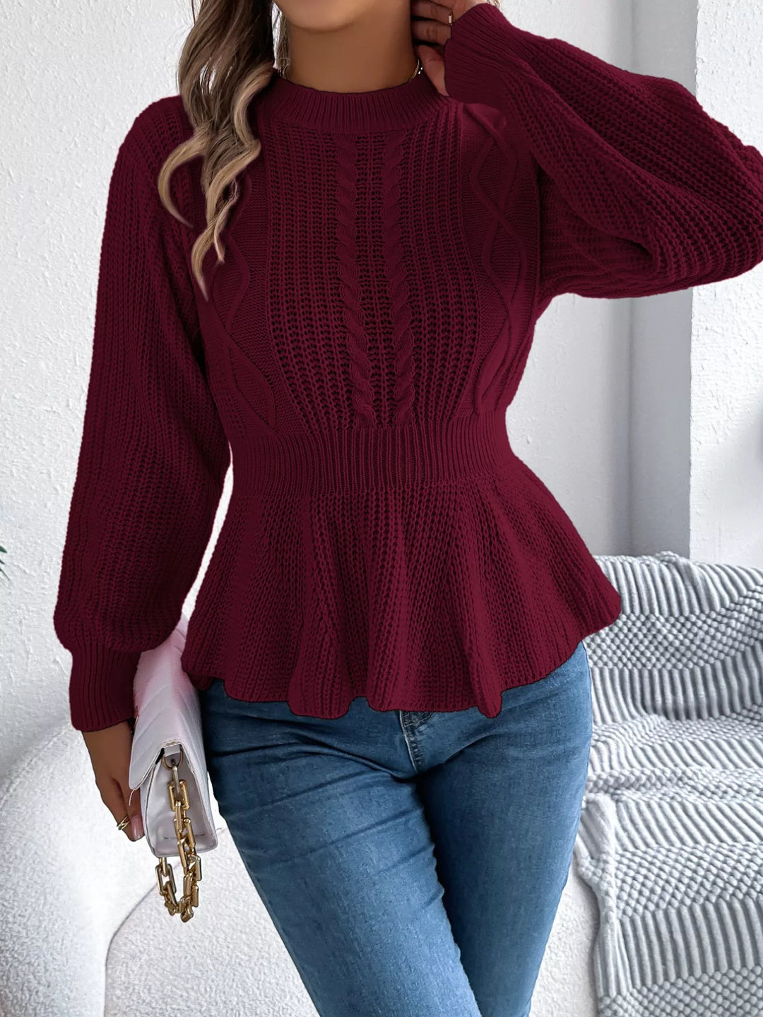 Burgundy peplum sweater with a bag at the hip, side angle