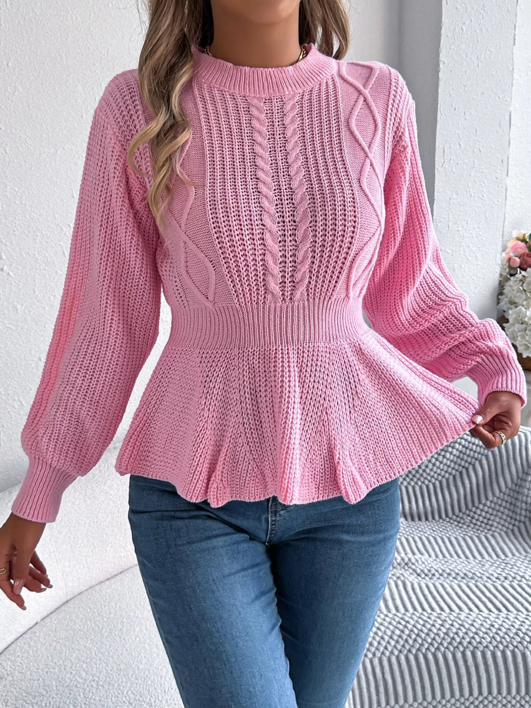Pink peplum ruffle sweater with hand on the hem, full length with jeans