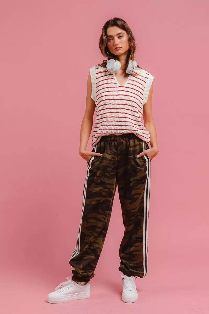 Full length view of camo track pants styled with a striped vest and sneakers