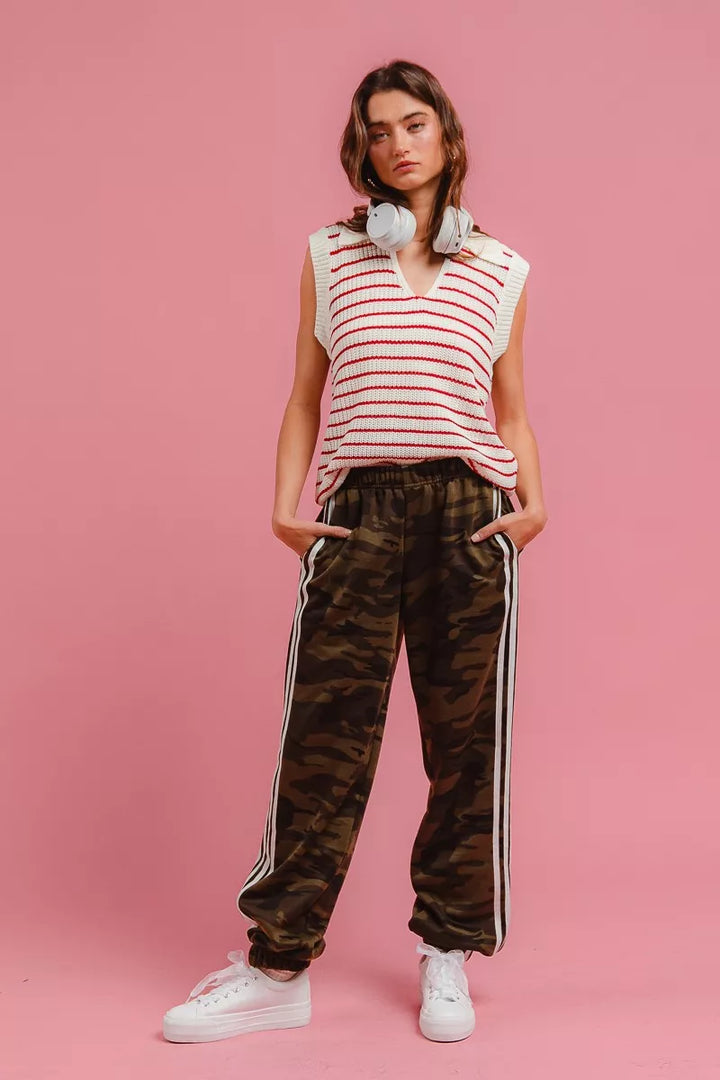 Full length view of camo track pants styled with a striped vest and sneakers