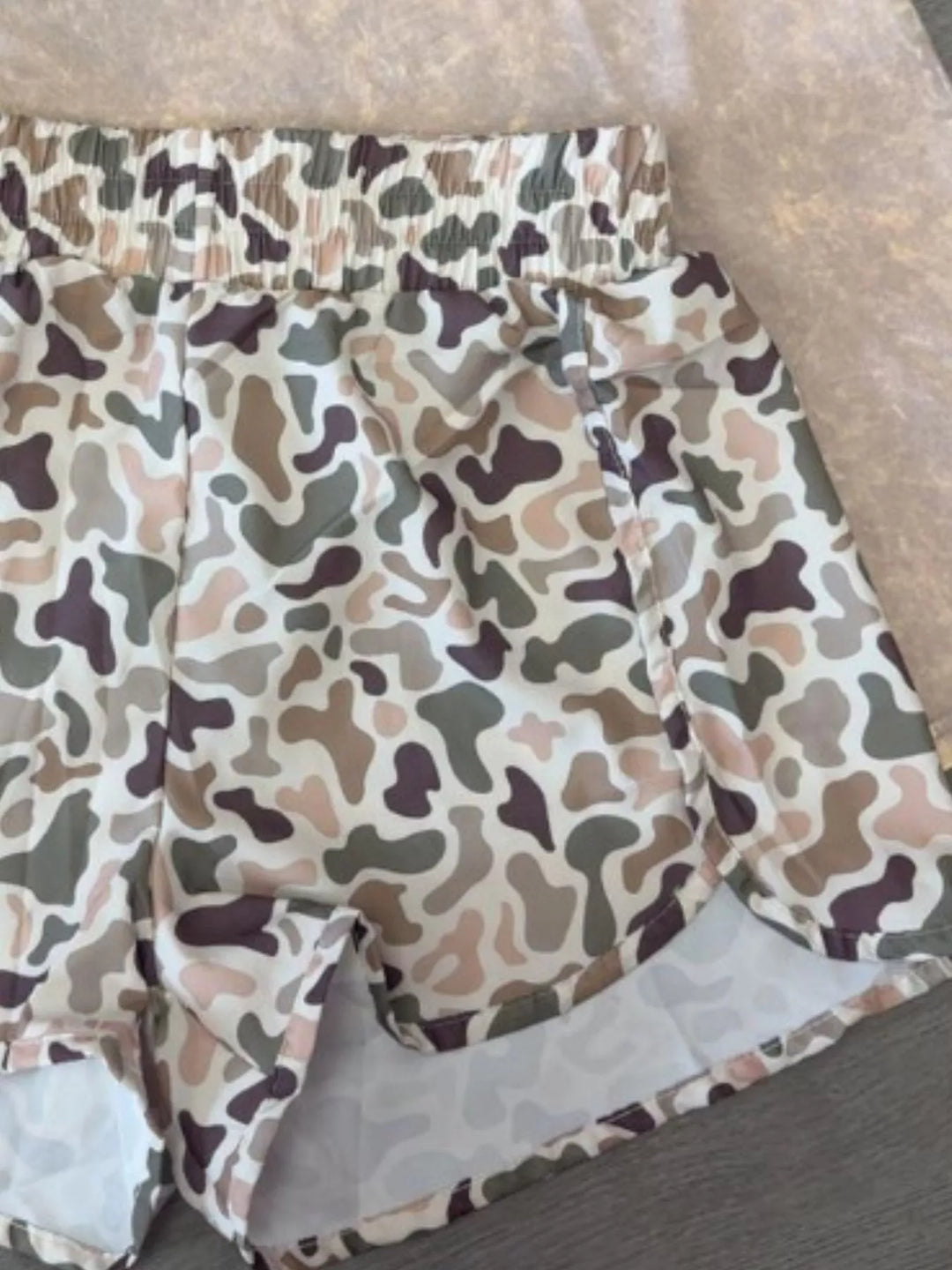 Beige camo shorts close-up of the waistband and curved hem edge