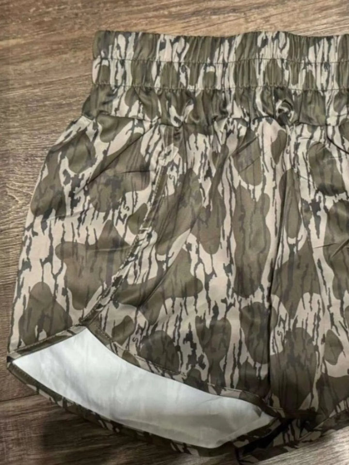 Olive camo high waisted shorts laid flat showing the white lining at the hem