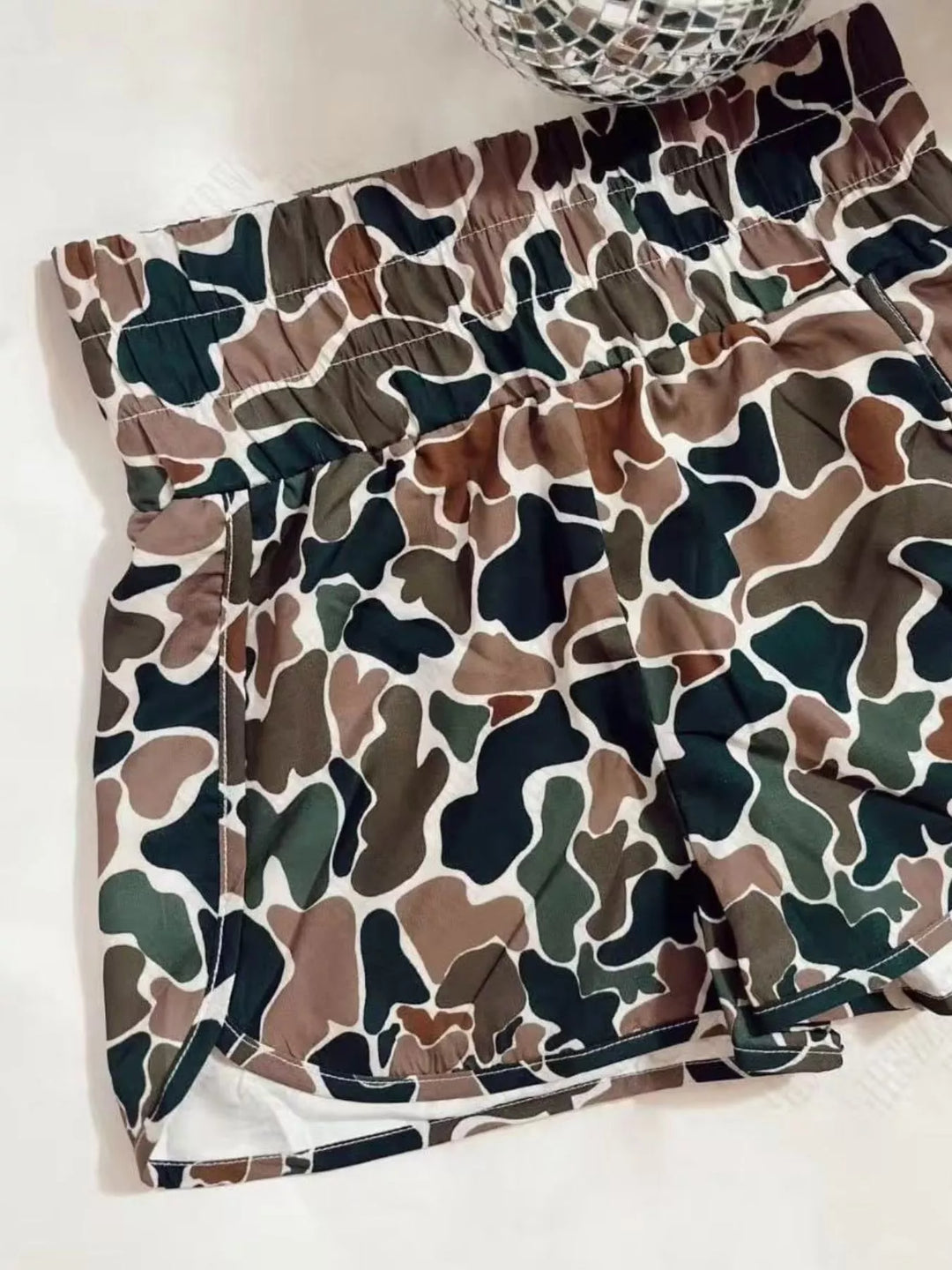 Woodland camo high waisted shorts laid flat with curved tulip hem