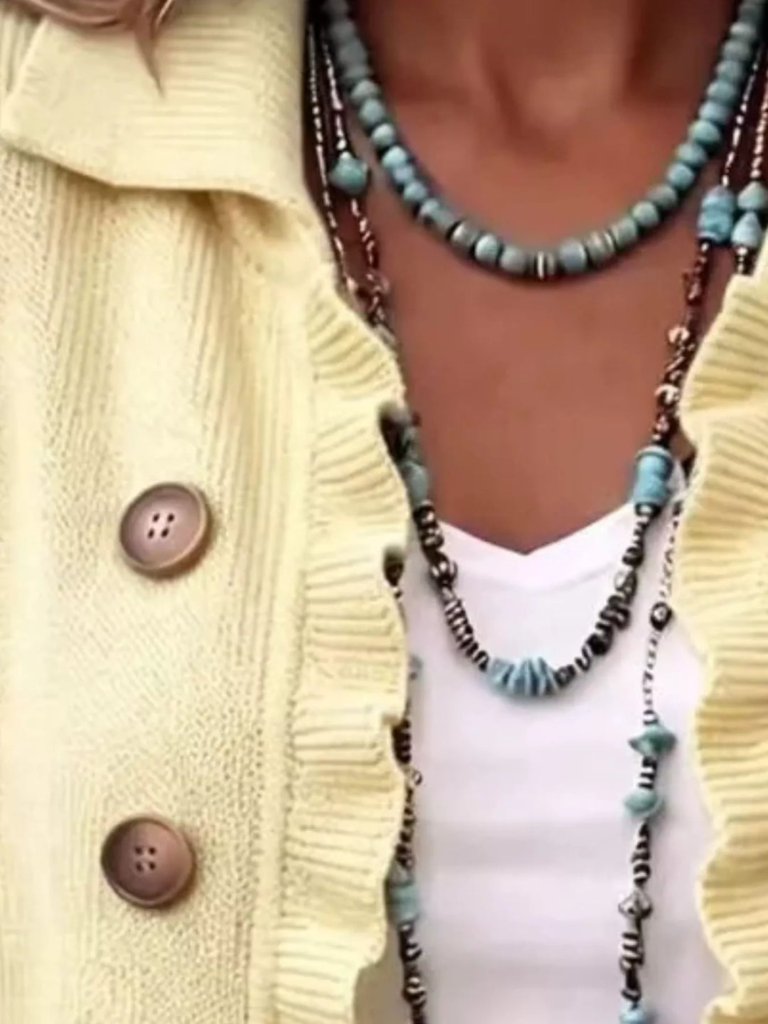 Pale yellow ruffle trim cardigan close-up of the collar and layered necklaces