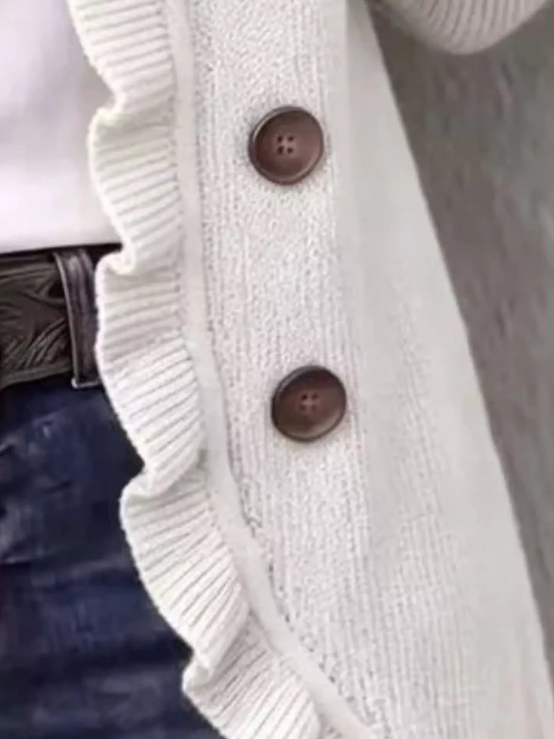 White cardigan detail of the ruffle trim and brown buttons up close