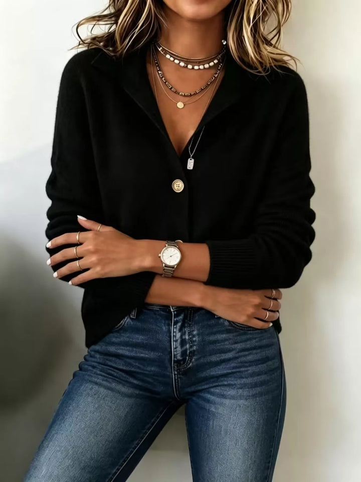 Black knit cardigan with arms crossed and a watch on the wrist