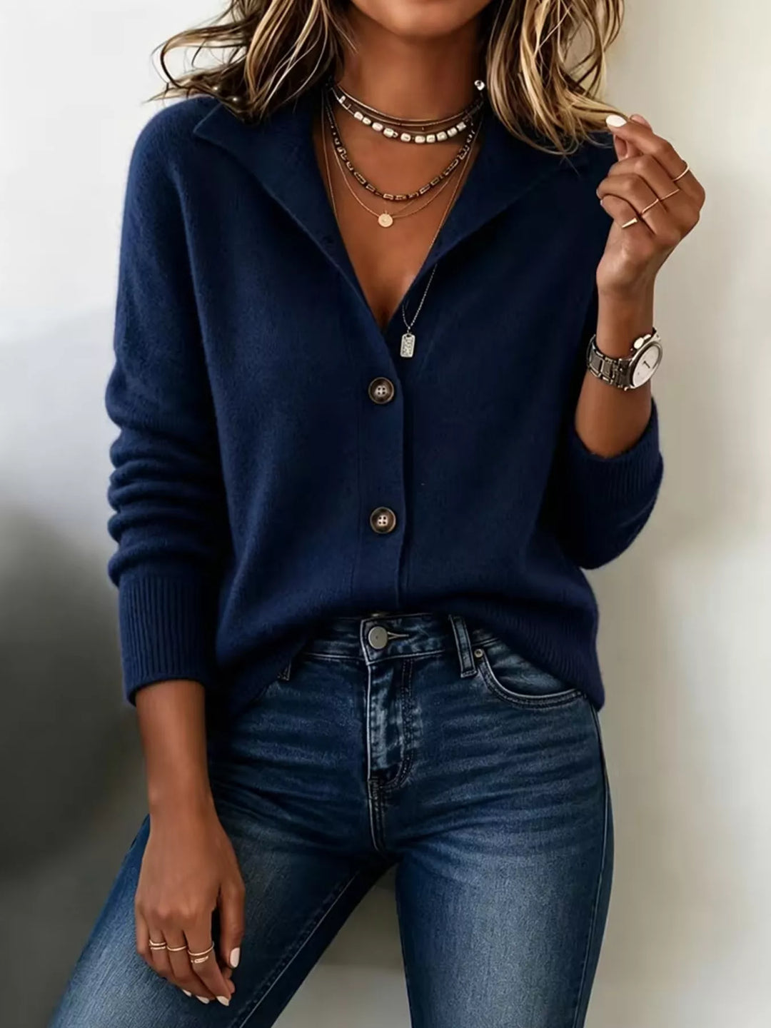 Navy button front cardigan with hand raised to the collar