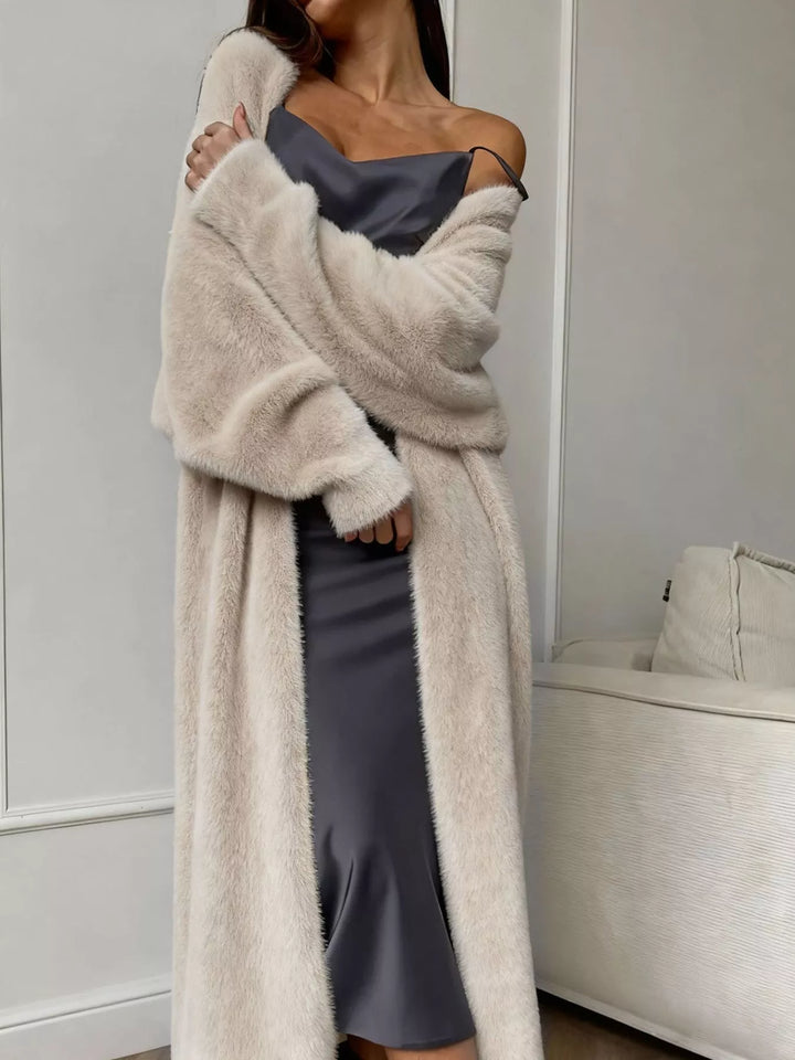Beige fuzzy longline cardigan with dropped shoulders worn open over a satin dress