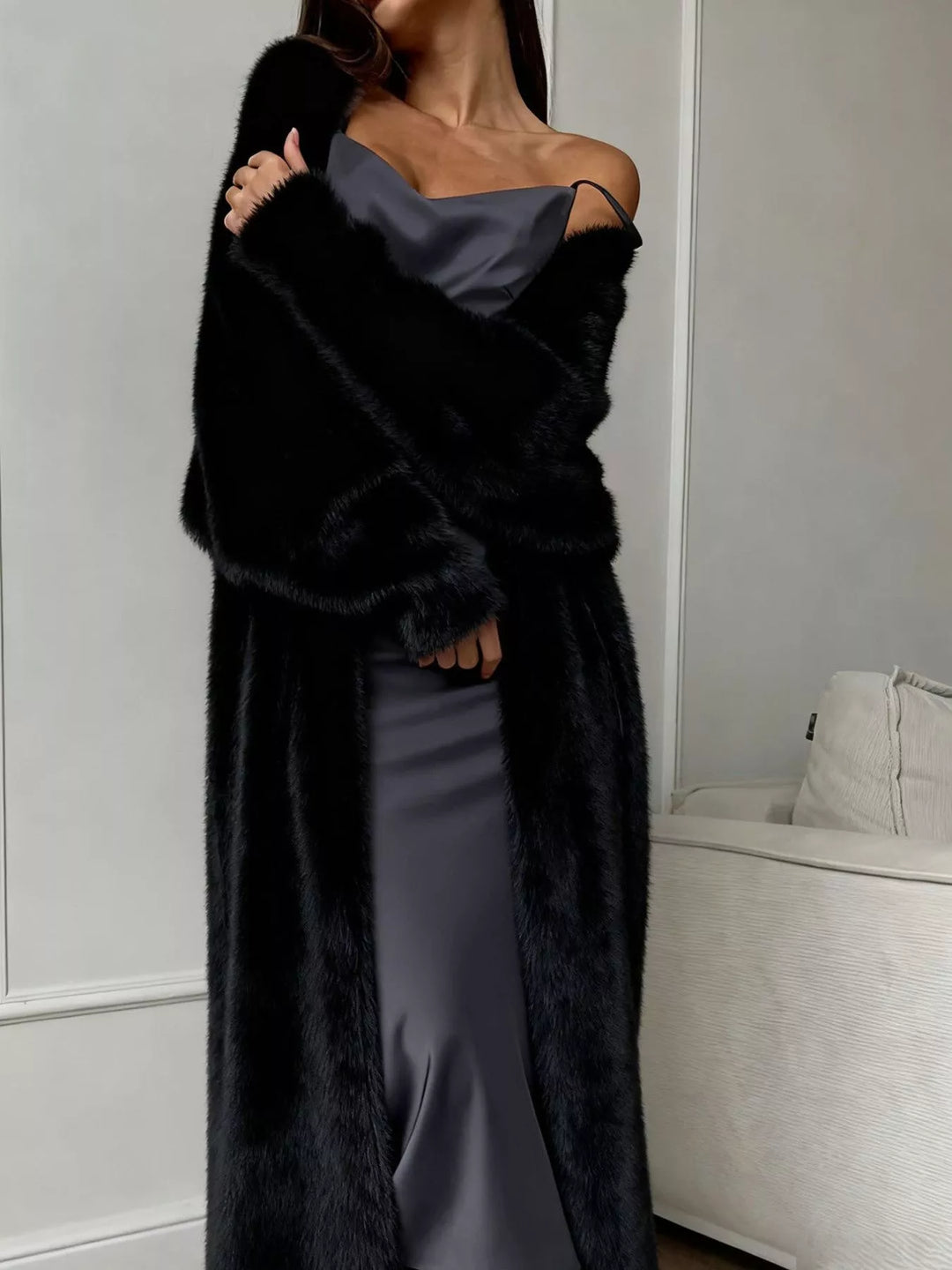 Black fuzzy longline cardigan worn open over a satin slip dress