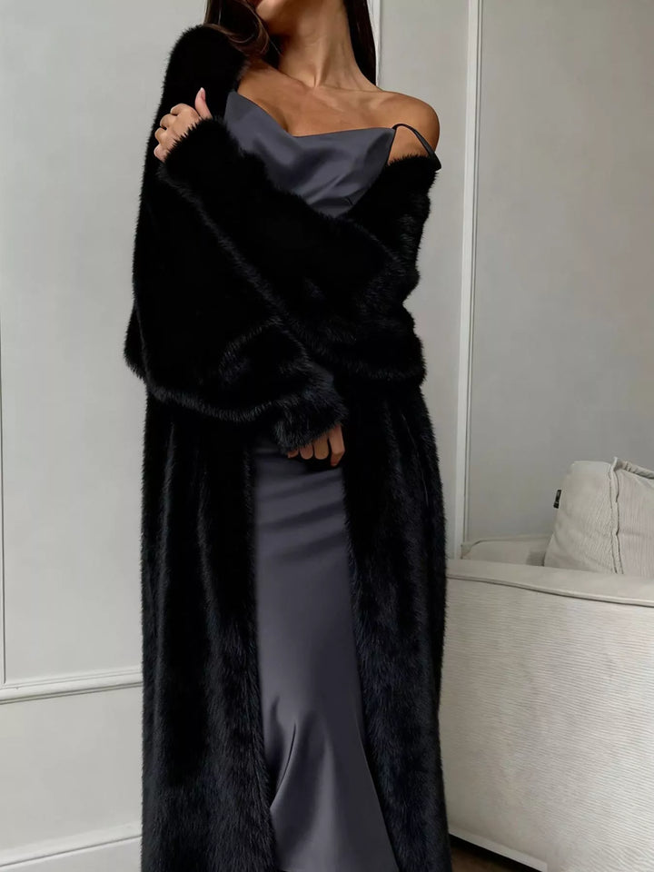 Black fuzzy longline cardigan worn open over a satin slip dress