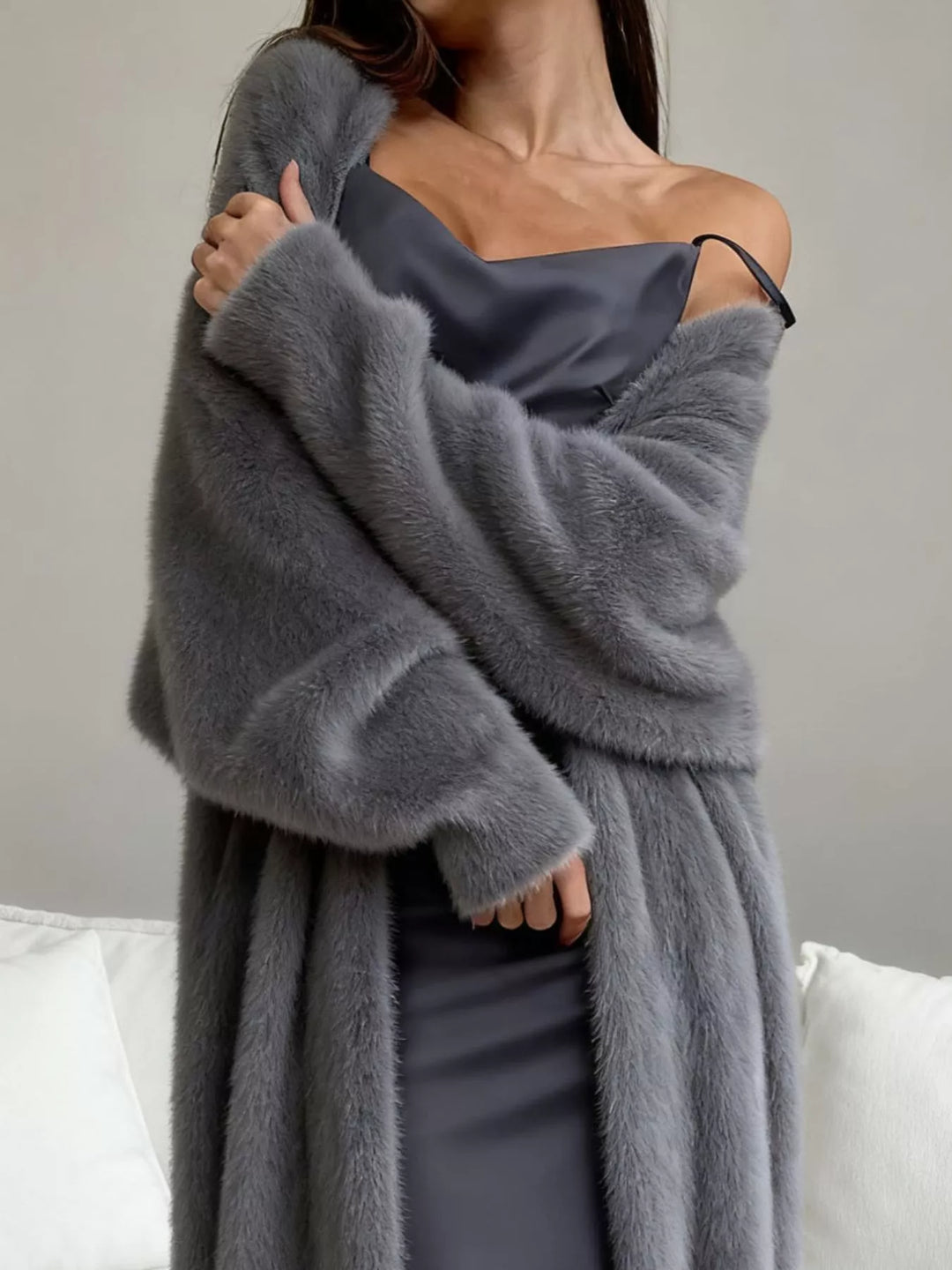 Close-up of gray fuzzy cardigan draped off the shoulder with crossed arms