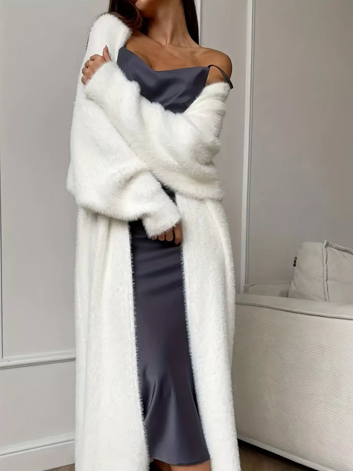 Ivory fuzzy cardigan worn off one shoulder with arm crossed
