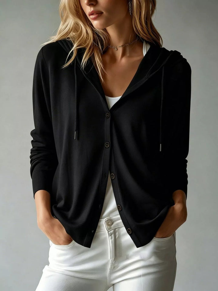 Black hooded cardigan with button front, worn over white jeans