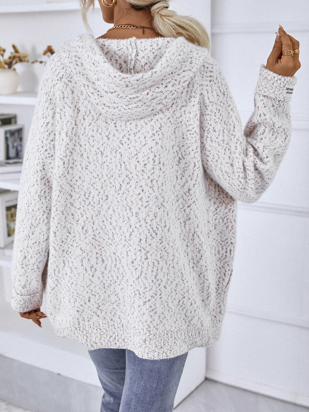 Back view of white hooded cardigan with raised arm