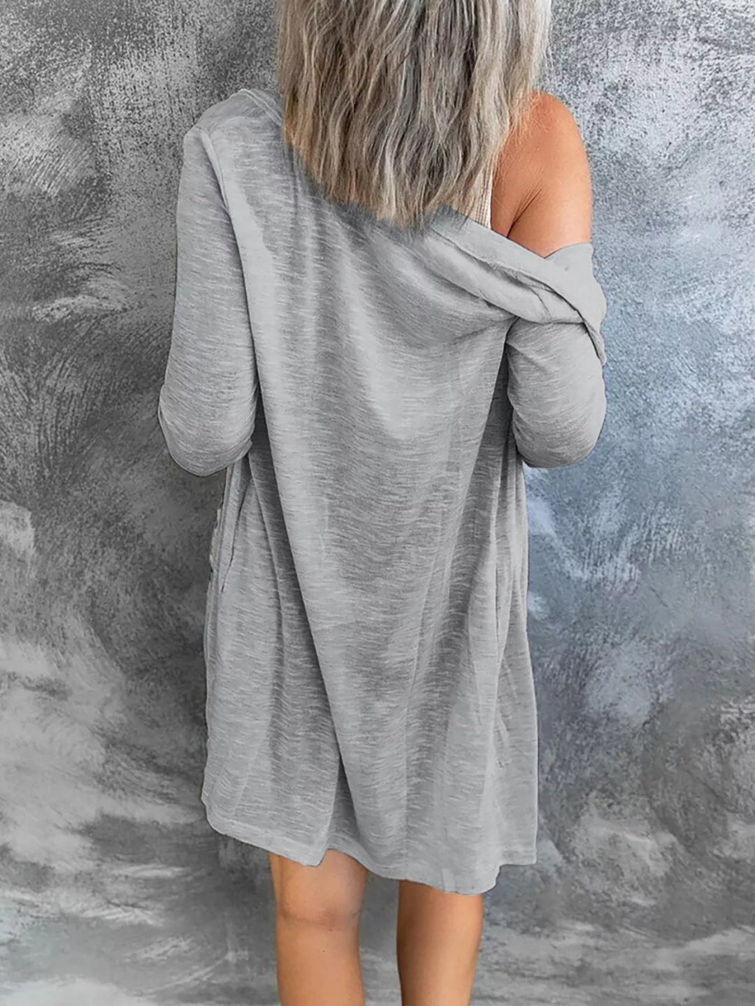 Gray longline cardigan seen from behind, slipping off one shoulder