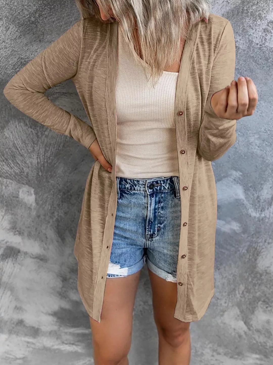 Longline tan button front cardigan with hand on hip, front view