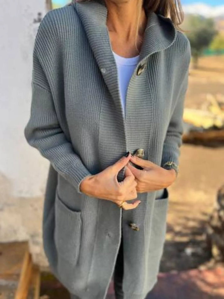 Sage chunky knit cardigan styled open with hands at the buttons