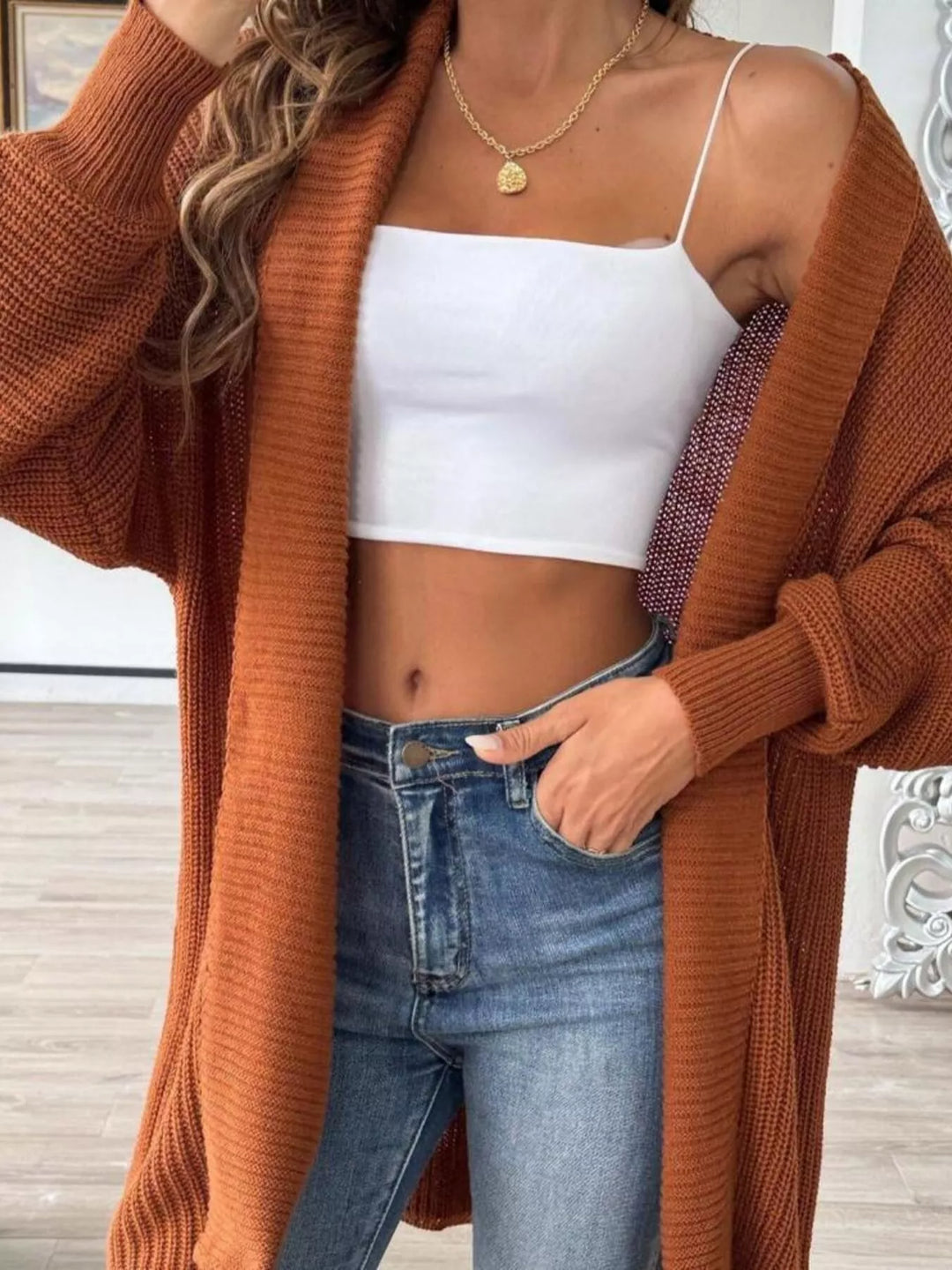 Close-up of the rust ribbed open front cardigan with balloon sleeve and white top