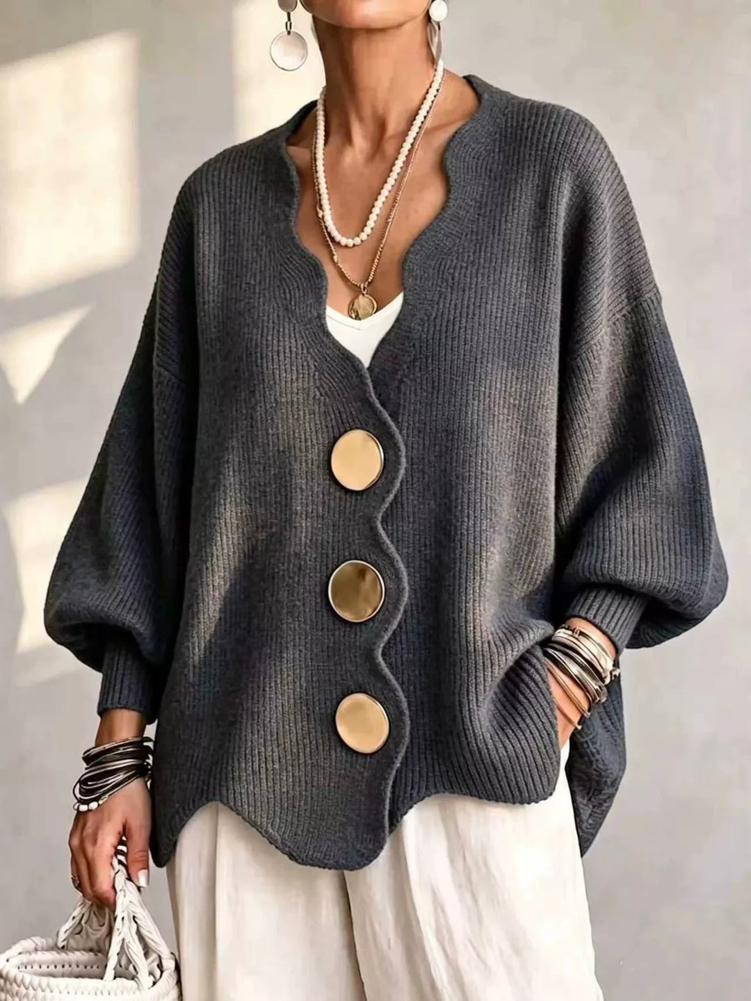 Oversized scalloped edge cardigan in charcoal with gold buttons, worn over white pants