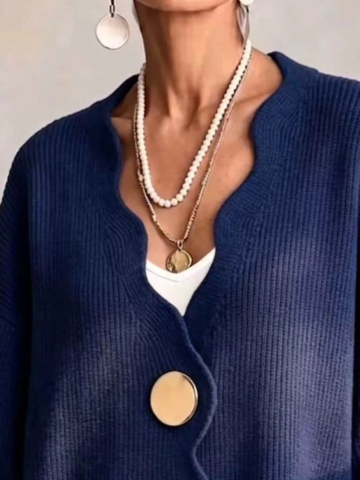 Close-up of the navy cardigan wavy neckline layered with pearl necklaces