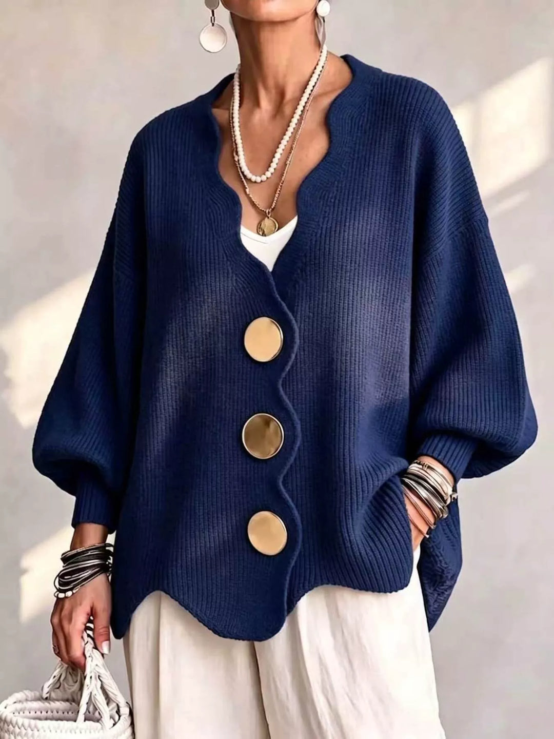 Oversized scalloped edge cardigan in navy with gold buttons, worn over white pants