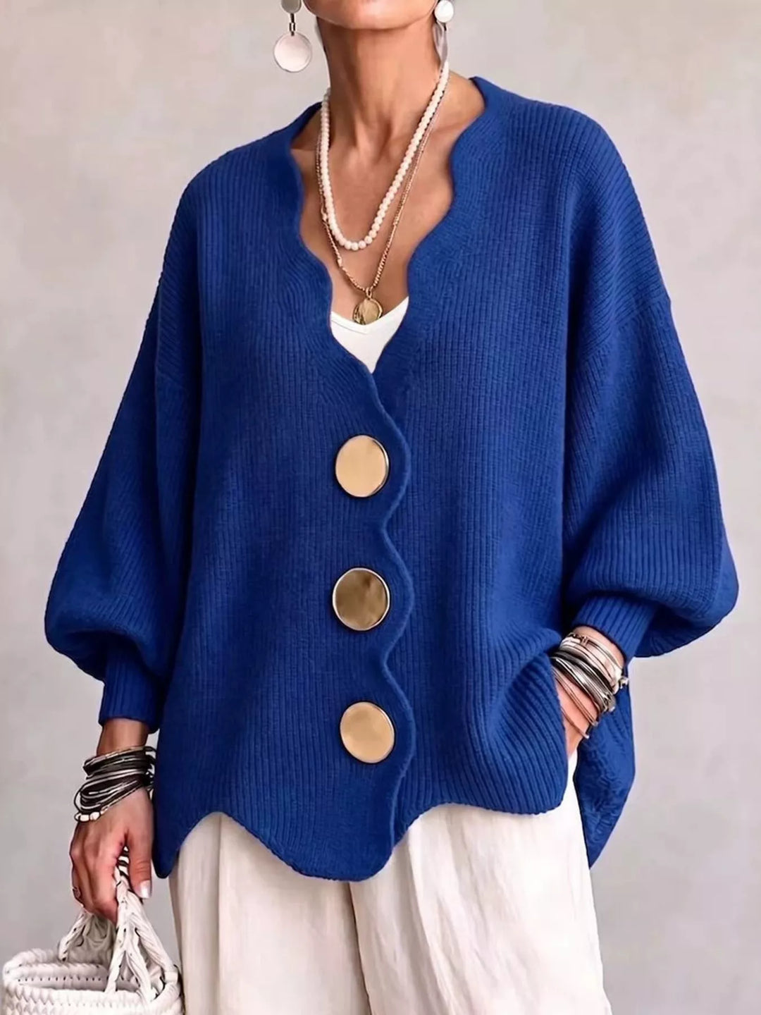 Oversized scalloped edge cardigan in royal blue with gold buttons, worn over white pants