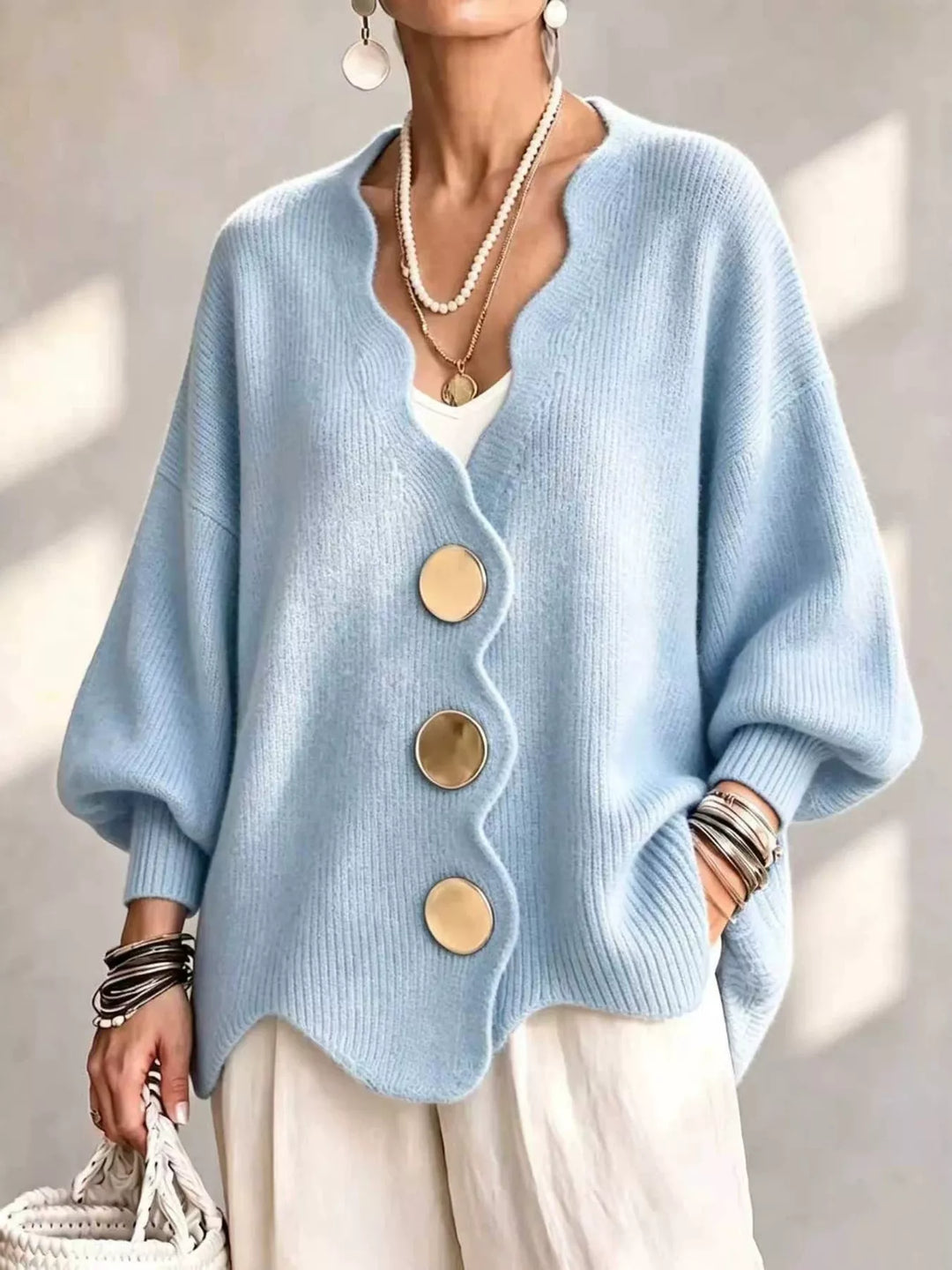 Oversized scalloped edge cardigan in sky blue with gold buttons, worn over white pants