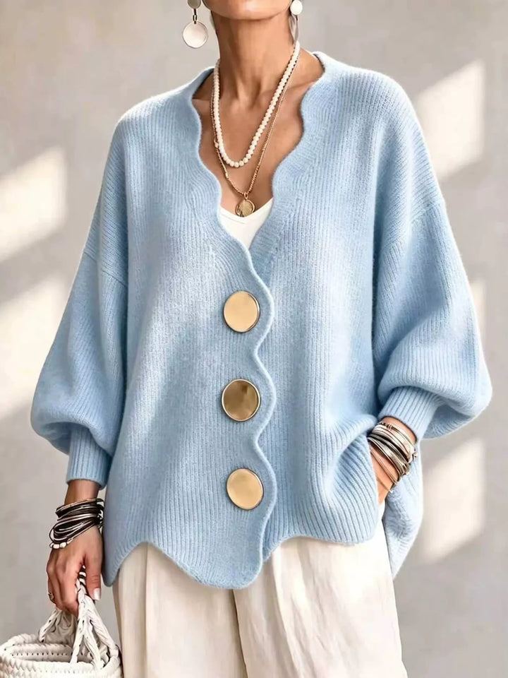 Oversized scalloped edge cardigan in sky blue with gold buttons, worn over white pants