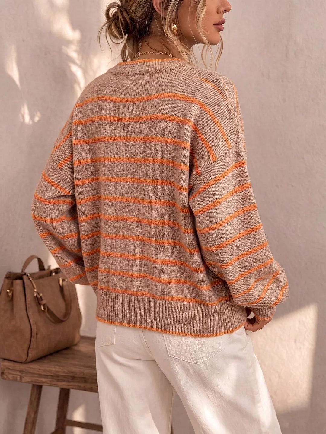 Back view of the camel striped cardigan with orange stripes beside a brown bag