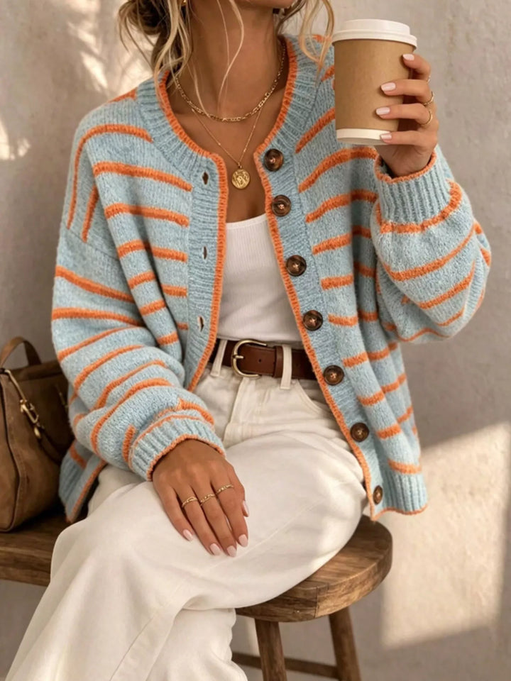 Women's cardigan in light blue with orange stripes, button front crew neck, holding a coffee
