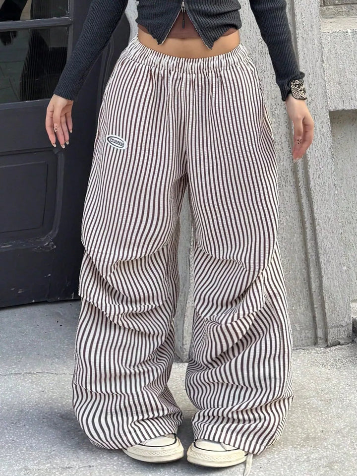 Brown stripe wide leg pants outdoors with white sneakers, front view