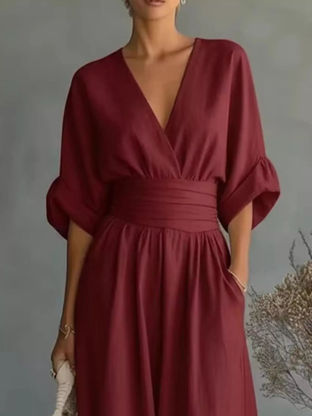 Close-up of the burgundy jumpsuit with a wide waistband and rolled sleeves