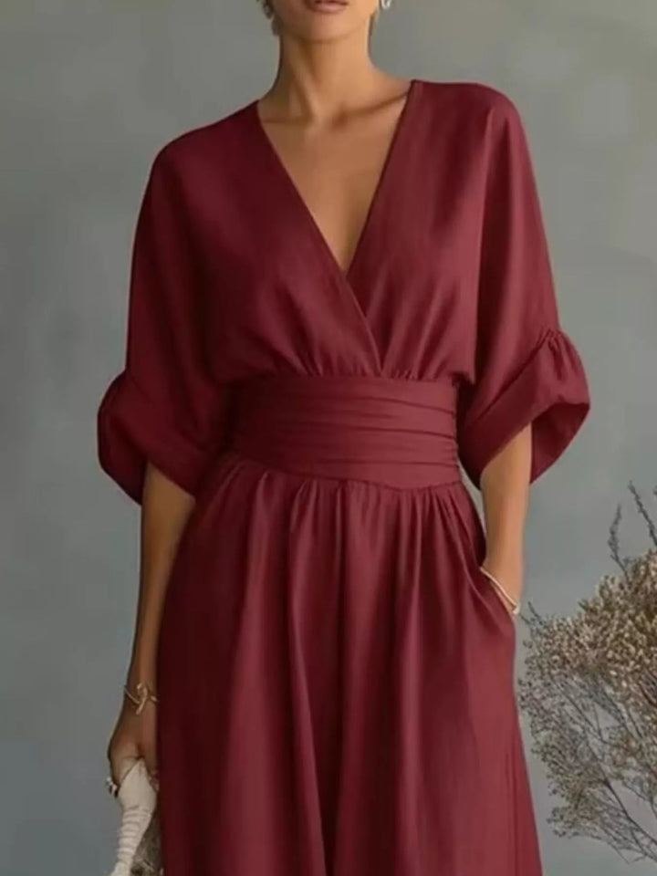 Close-up of the burgundy jumpsuit with a wide waistband and rolled sleeves