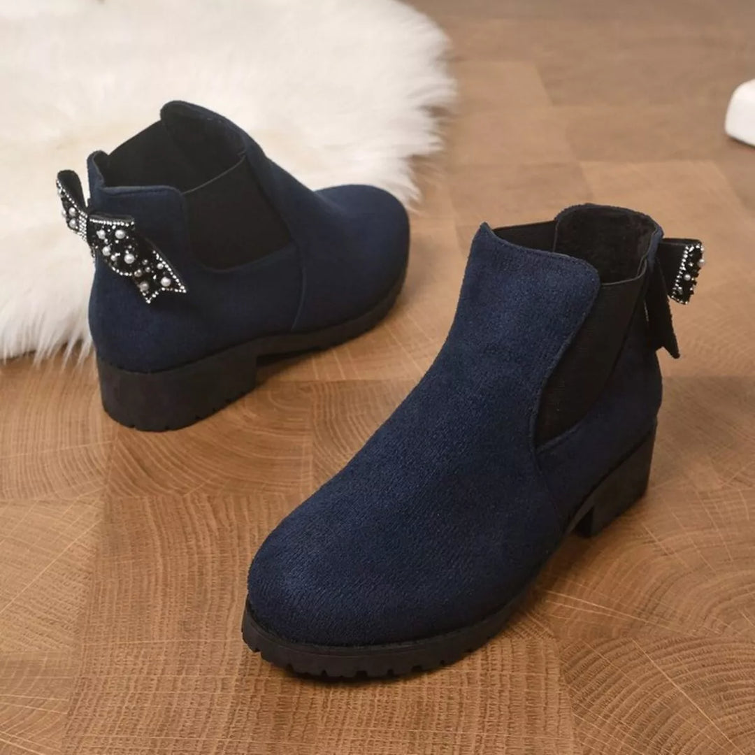 Navy lug sole Chelsea boots shown side by side on a rug