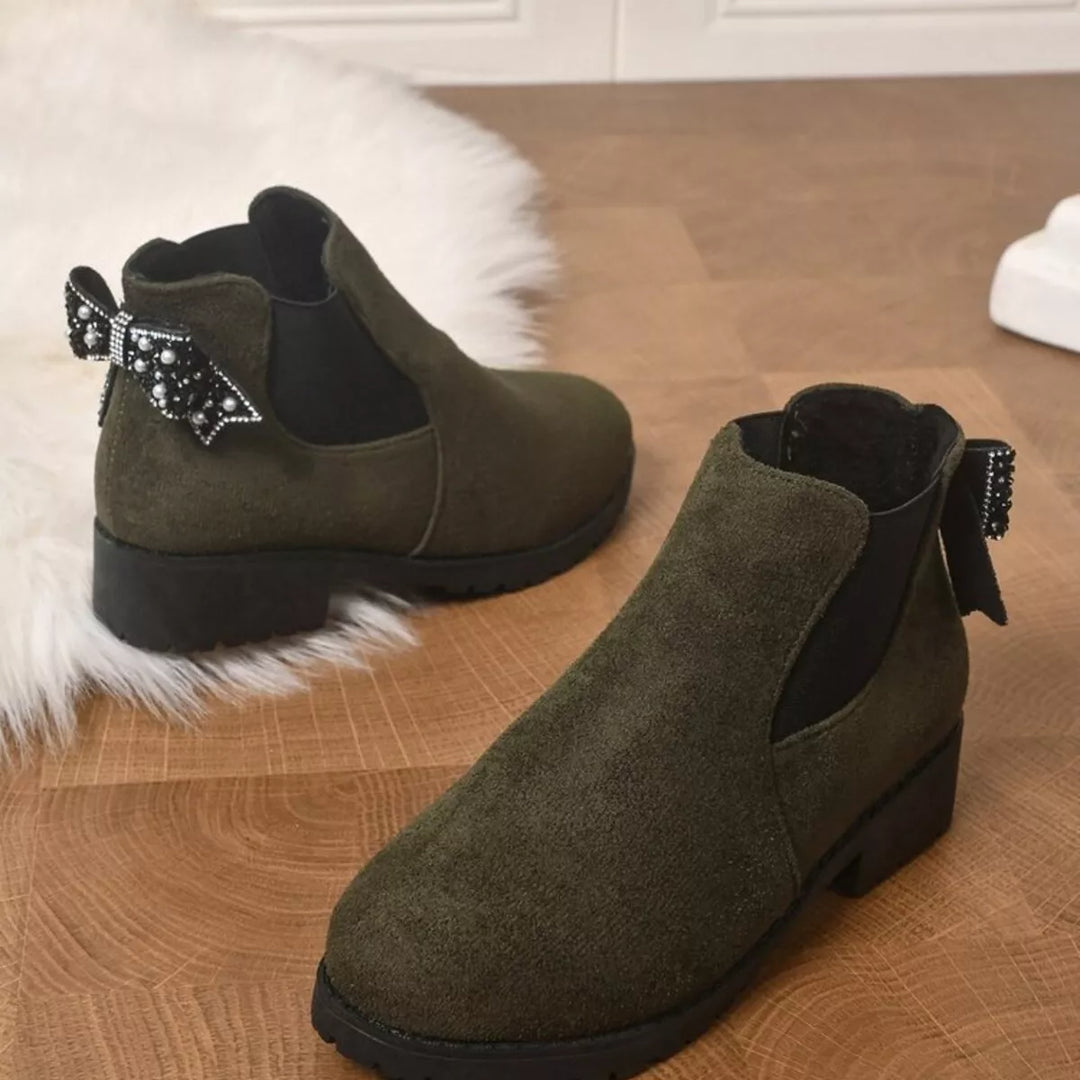 Pair of olive Chelsea boots on a fluffy rug, side and front view
