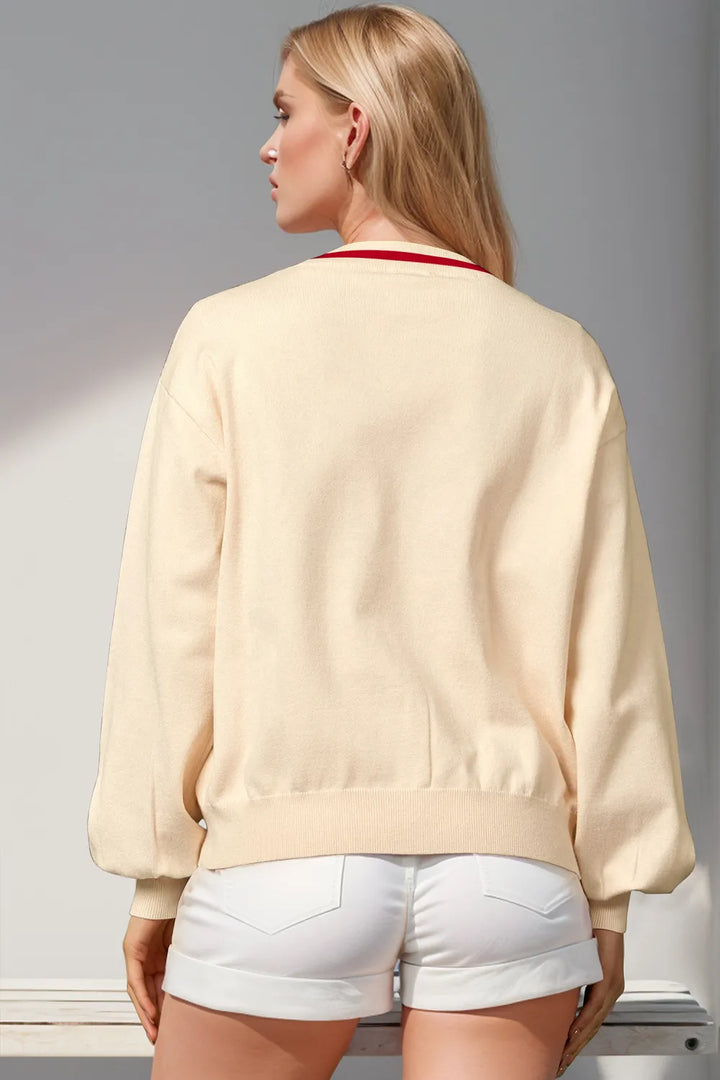 Back view of the cream V neck cardigan with red trim at the neckline