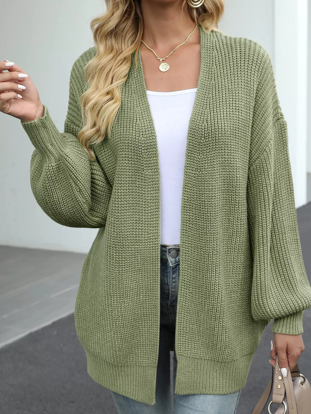Sage green cardigan worn open with jeans and a small handbag