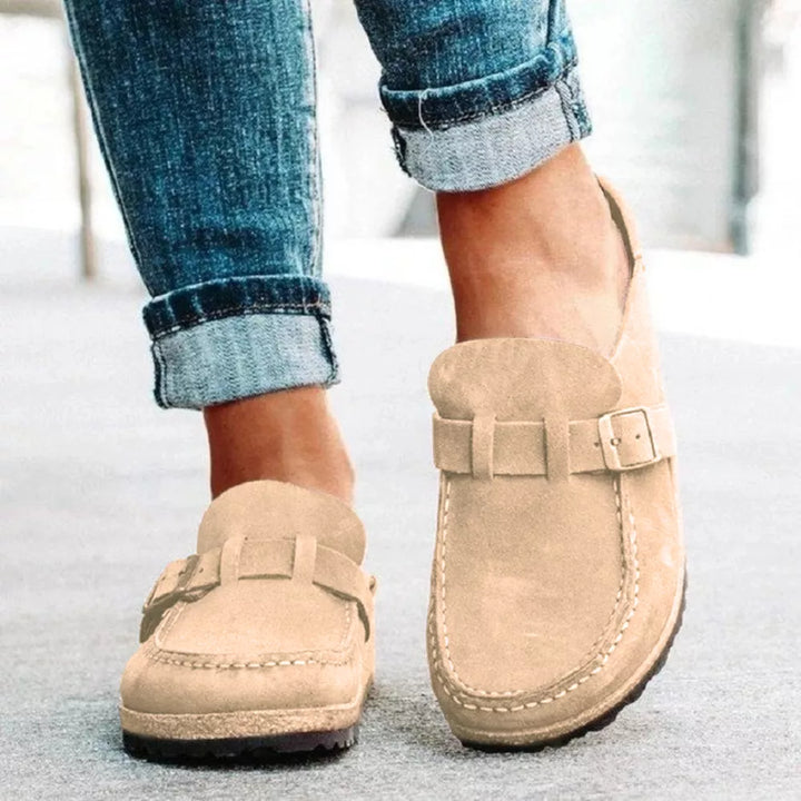 Women's clogs in beige, backless slip on with buckle strap, worn with cuffed jeans
