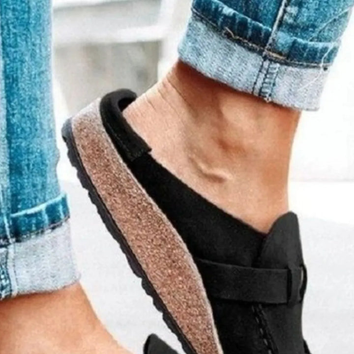 Black wedge clog seen from the side showing the heel cup and sole