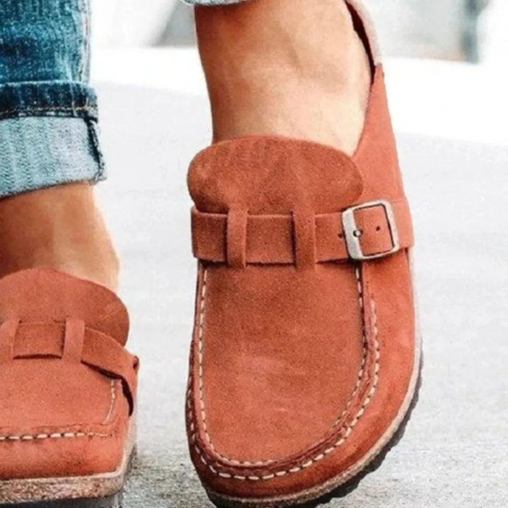 Close-up of the rust backless clog with buckle strap and visible stitching