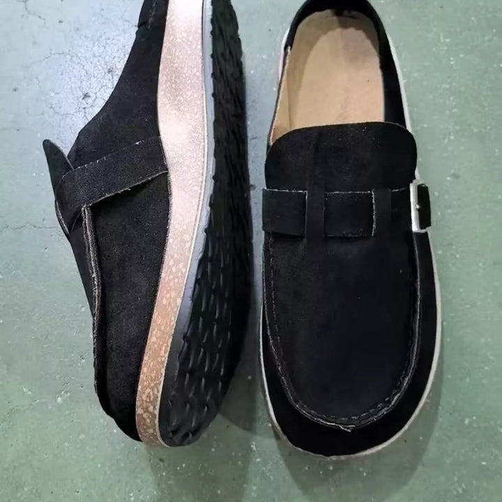 Black clogs with buckle strap seen from above, cork-look footbed visible