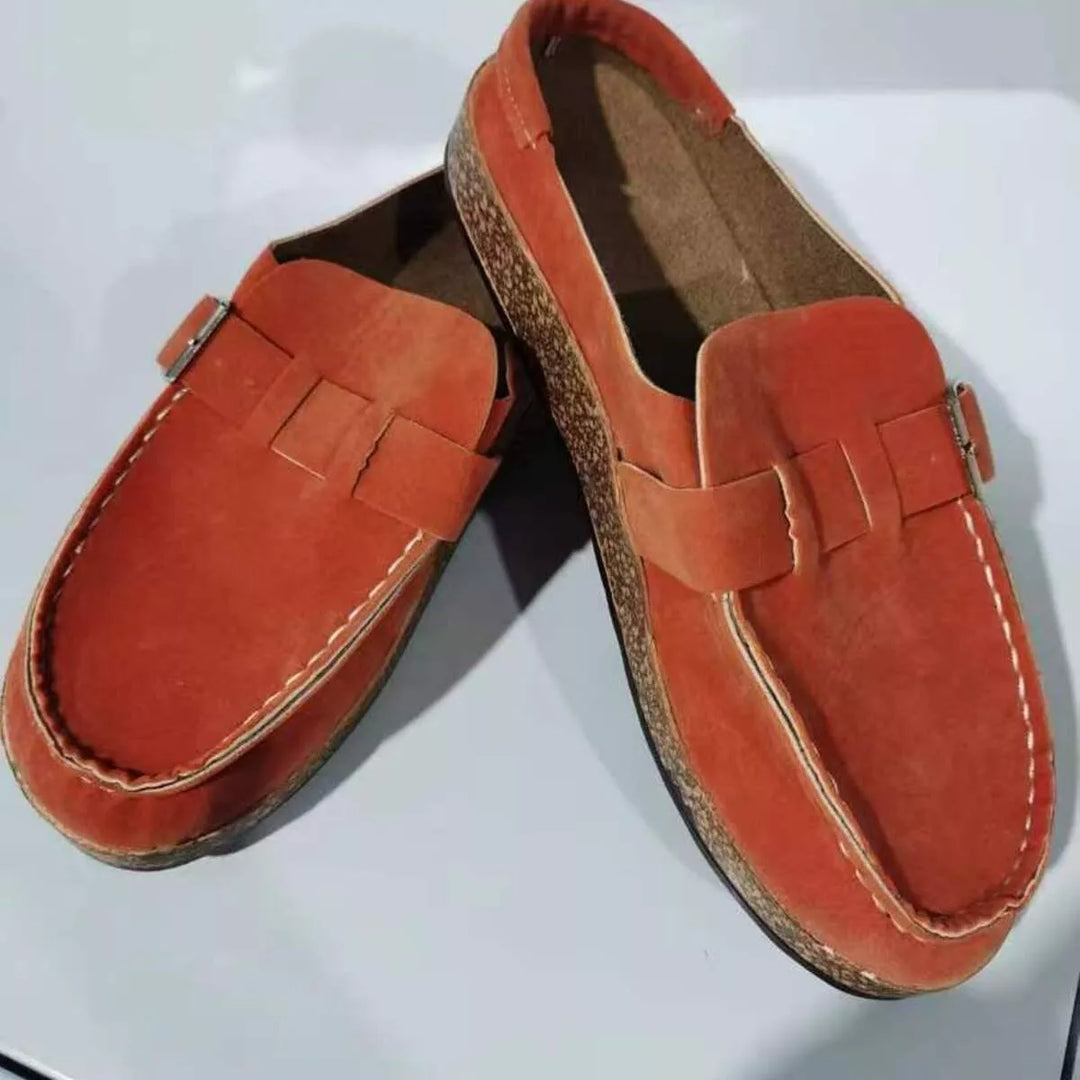 Pair of rust clogs with buckle strap and cork-look footbed, angled view