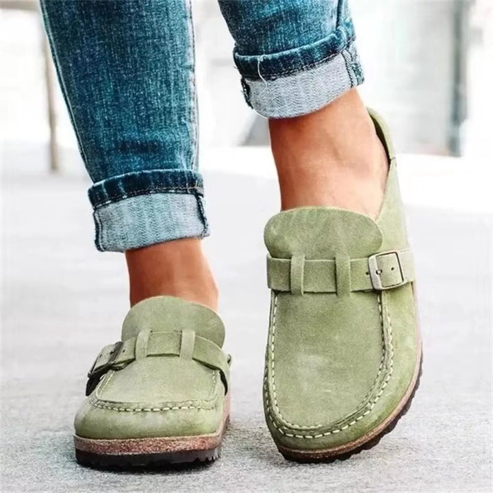 Women's clogs in sage green with buckle strap, slip on style worn with cuffed jeans