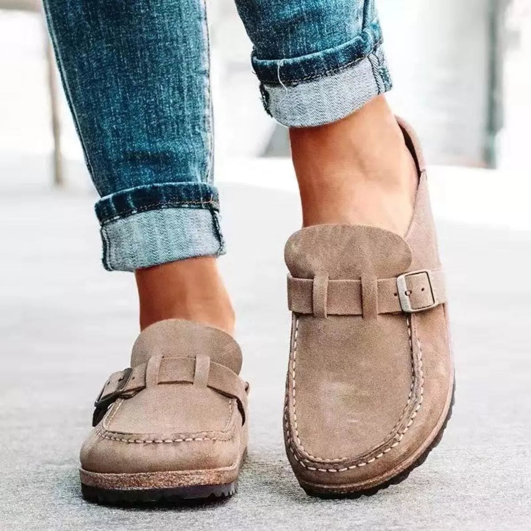 Taupe slip on clogs with buckle strap worn with rolled jeans, front view