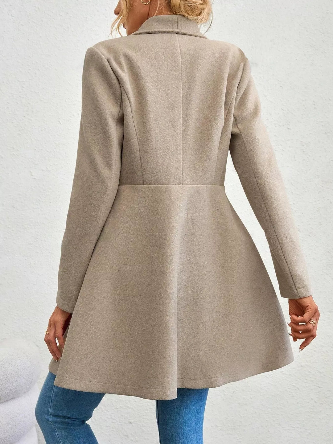 Back view of the beige fit and flare coat with seamed waist