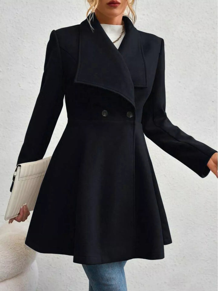 Black double breasted coat with wide lapel and flared skirt, holding a clutch