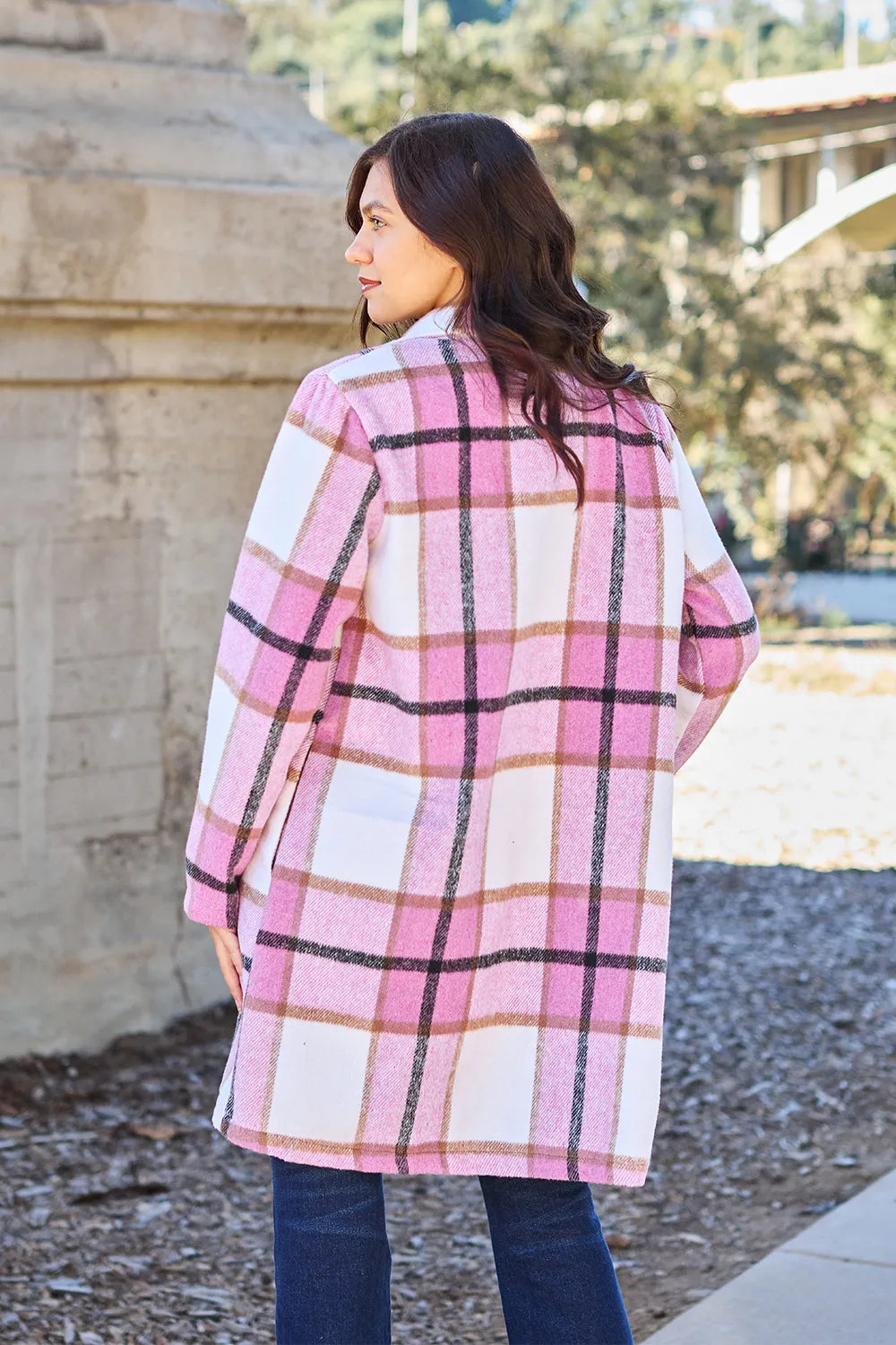 Back view of pink plaid mid length coat on a model outdoors