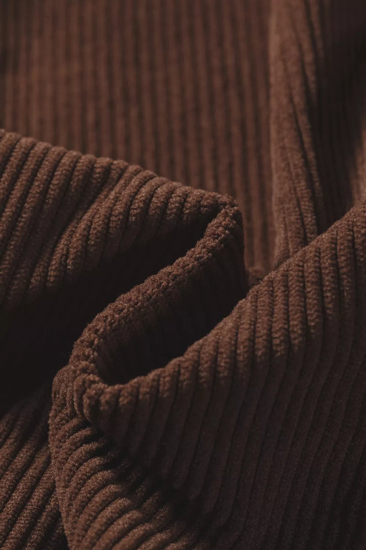 Ribbed texture and folded fabric of the dark brown corduroy shirt up close