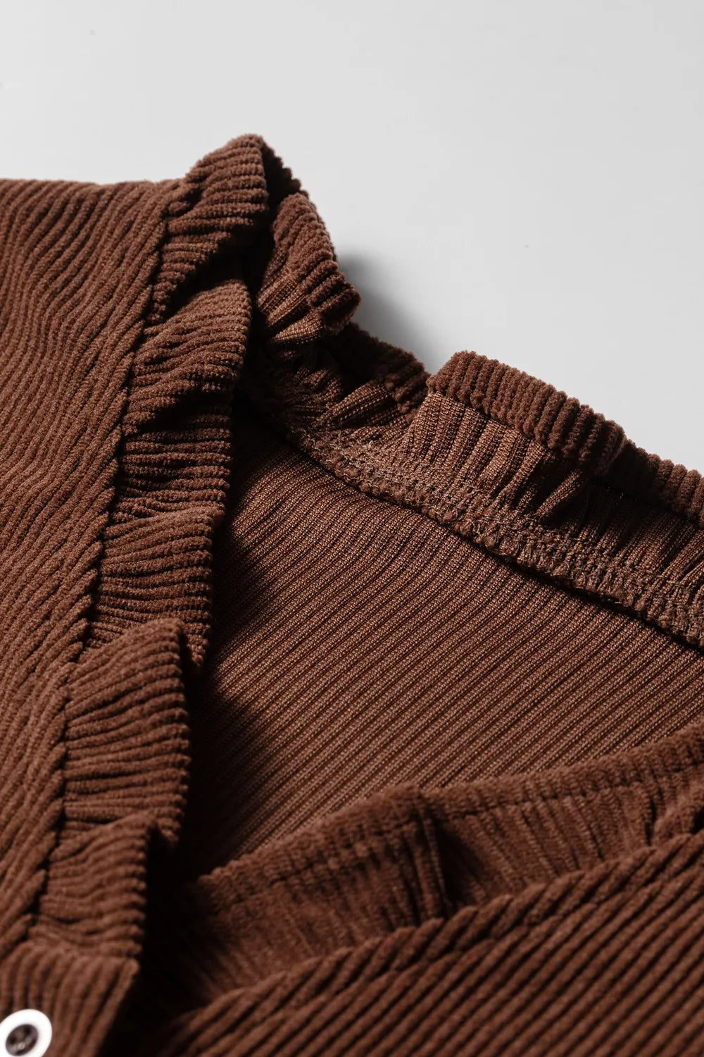 Close-up of the ruffle trim along the neckline of the brown corduroy blouse