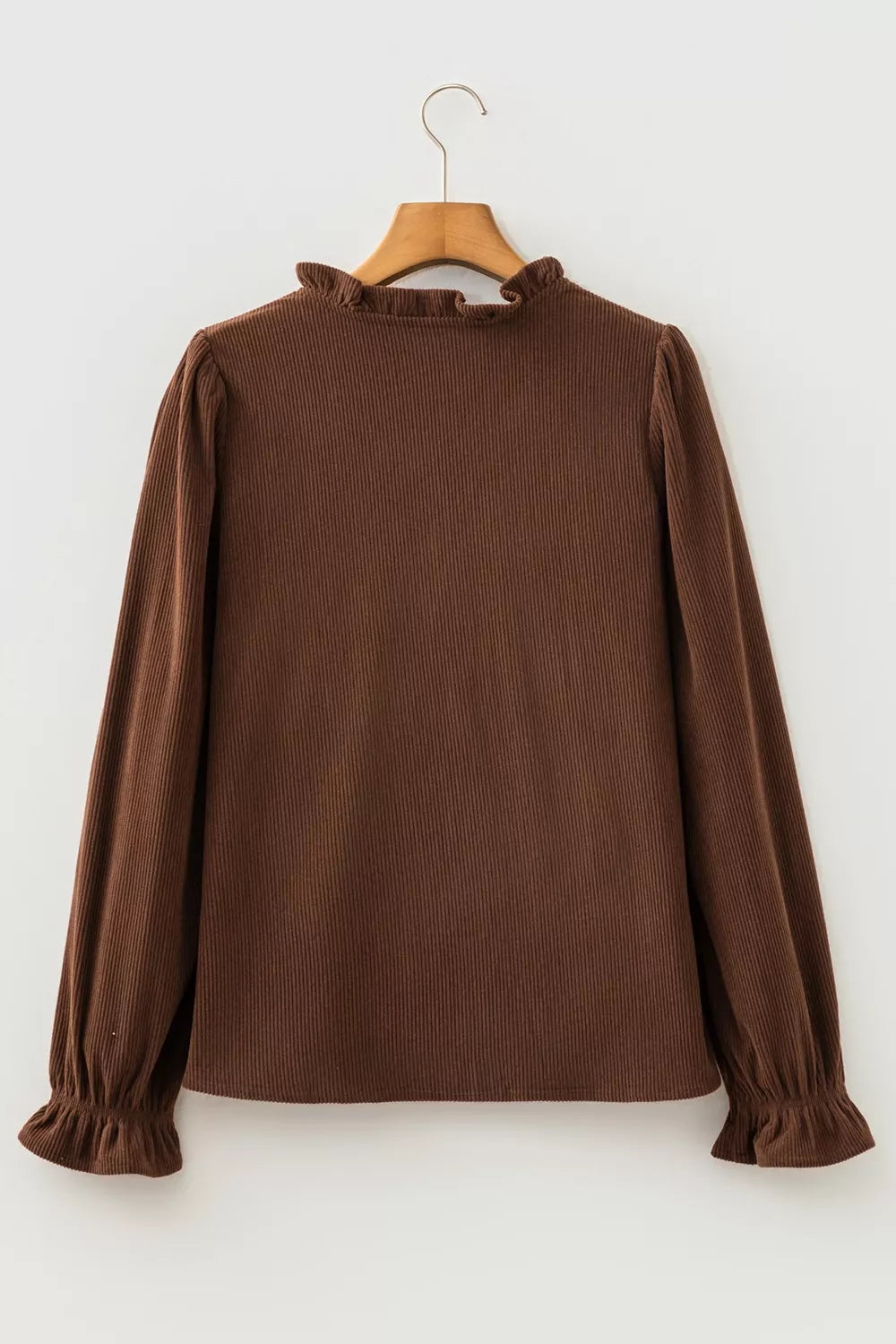Back of the dark brown corduroy blouse on a hanger with ruffle collar